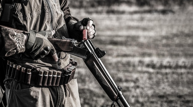 El hombre está cargando un rifle de caza Cazador masculino listo para cazar Primer plano El hombre está en el deporte de caza Hombre cazador Período de caza Hombre con un rifle de pistola Blanco y negro