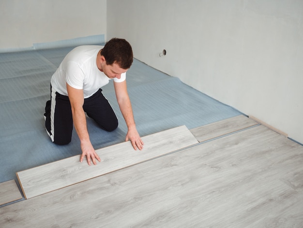 Un hombre está colocando pisos laminados. El proceso de reparación en la sala.