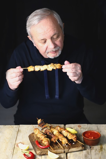 El hombre está comiendo una brocheta de pollo.