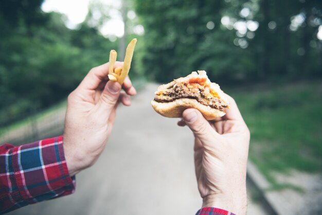 El hombre está comiendo en el parque y disfrutando de una deliciosa comida