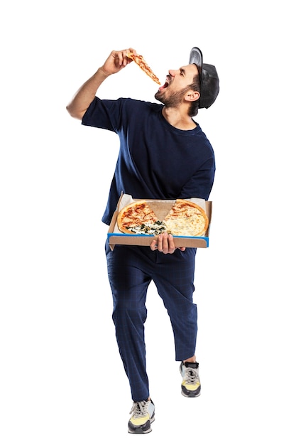 El hombre está comiendo una porción de pizza. Joven morena con barba y gorra. Entrega un bocadillo apetitoso. Aislado en el fondo blanco. Vertical. Altura completa.