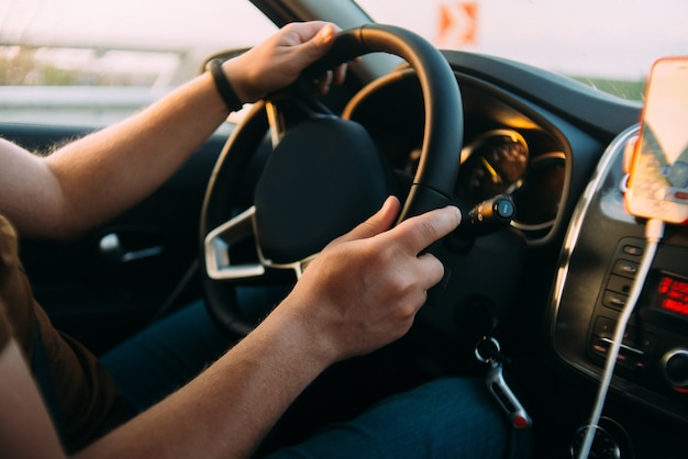 El hombre está conduciendo las manos del coche en el volante