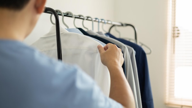 El hombre está eligiendo camisa en el cuarto de ropa en casa