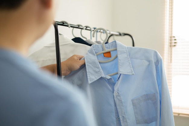 El hombre está eligiendo camisa en el cuarto de ropa en casa