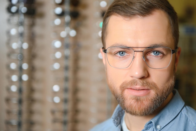 El hombre está eligiendo gafas en la tienda de óptica.