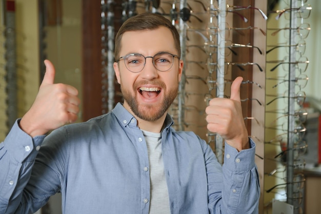 El hombre está eligiendo gafas en la tienda de óptica.