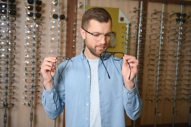 El hombre está eligiendo gafas en la tienda de óptica.