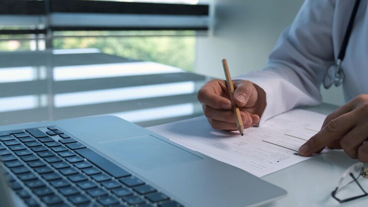 Un hombre está escribiendo en un pedazo de papel con una pluma.