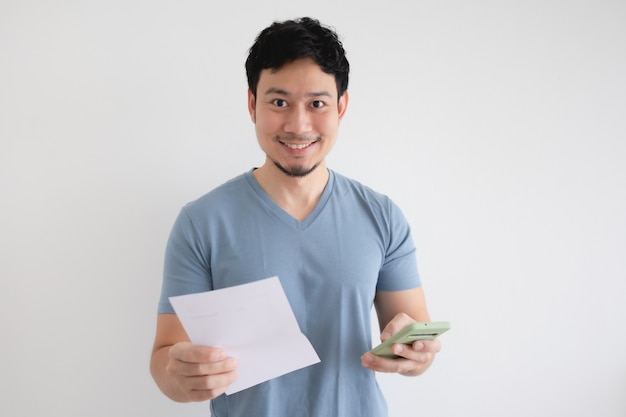 El hombre está feliz por el teléfono inteligente y la factura en una pared aislada