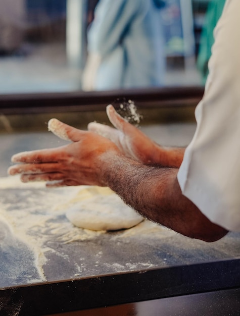 Un hombre está haciendo masa para pizza en una mesa.