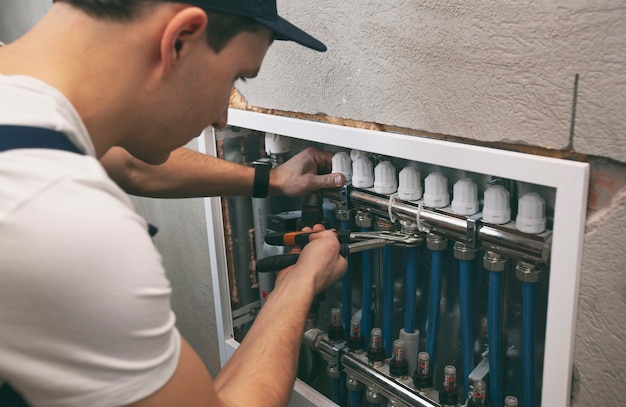 El hombre está instalando el sistema de calefacción en la casa.