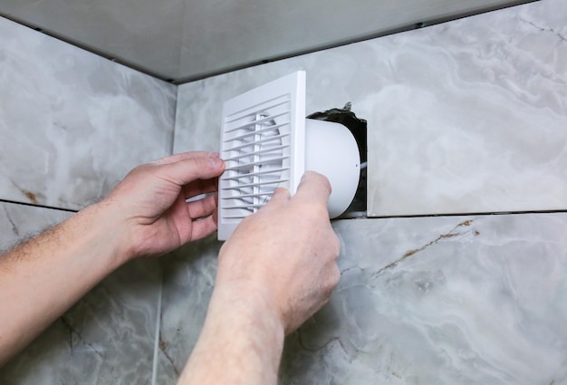 El hombre está instalando el ventilador de pared del baño Proceso de restauración