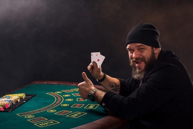 El hombre está jugando al póquer. El jugador de cartas emocional gana en el juego, el hombre está muy feliz de tomar las decisiones correctas, ganando todas las fichas en el banco.