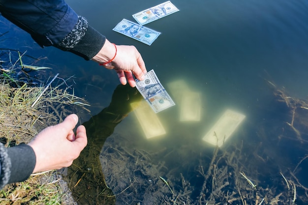 El hombre está lavando dólares en el río Lavado de dinero Manos en agua con billetes