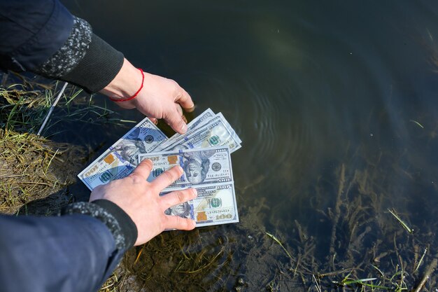 El hombre está lavando dólares en el río Lavado de dinero Manos en agua con billetes