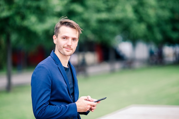 El hombre está leyendo un mensaje de texto en el teléfono móvil mientras camina en el parque