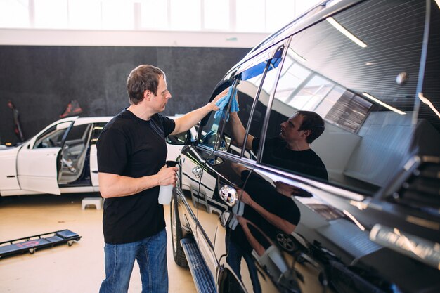 El hombre está limpiando con un cuerpo de tela de un auto brillante.