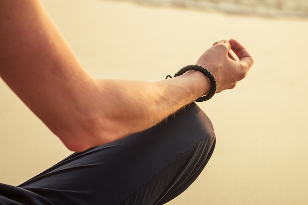 El hombre está meditando en la playa.