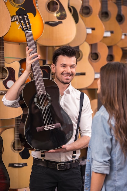 El hombre está mostrando a la guitarra chica en una tienda de música.