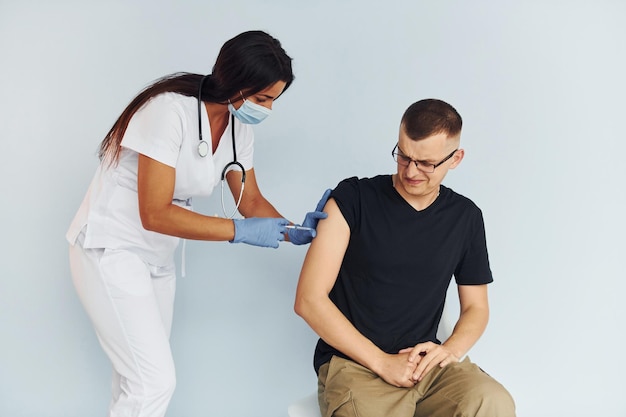 El hombre está nervioso Doctor en uniforme vacunando al paciente