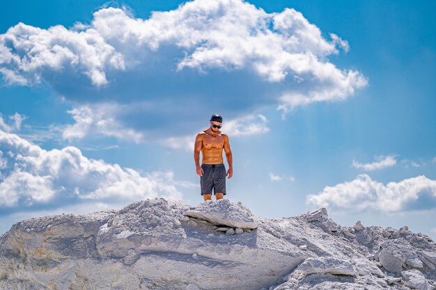 El hombre está de pie sobre una gran piedra blanca contra el cielo azul y las nubes
