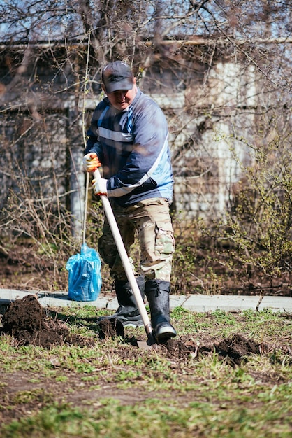 Un hombre está plantando un árbol joven El agricultor está cavando el suelo con una pala para una pequeña plántula El concepto de protección del medio ambiente y la ecología