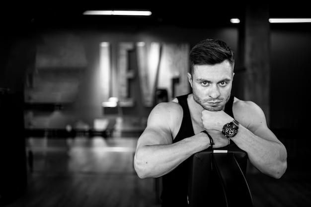 Hombre está posando en el gimnasio con las manos en el pecho