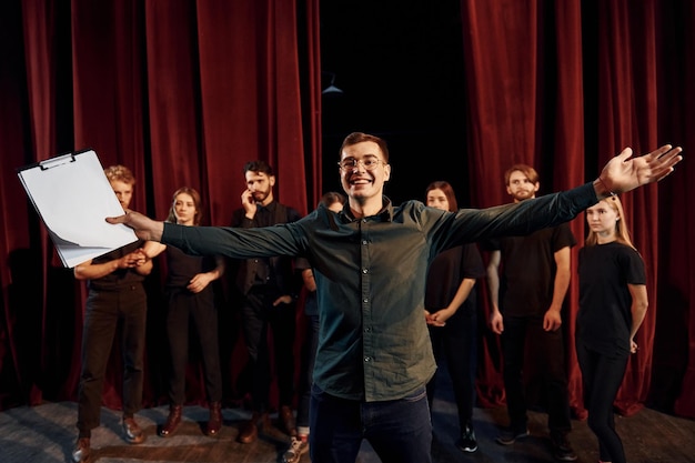 El hombre está practicando su papel un grupo de actores con ropa de color oscuro en el ensayo en el teatro