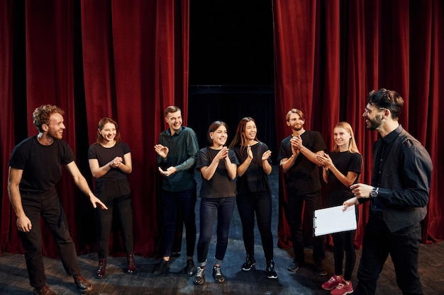 El hombre está practicando su papel Grupo de actores con ropa de color oscuro en el ensayo en el teatro