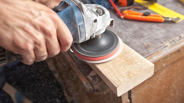 El hombre está puliendo el panel de madera