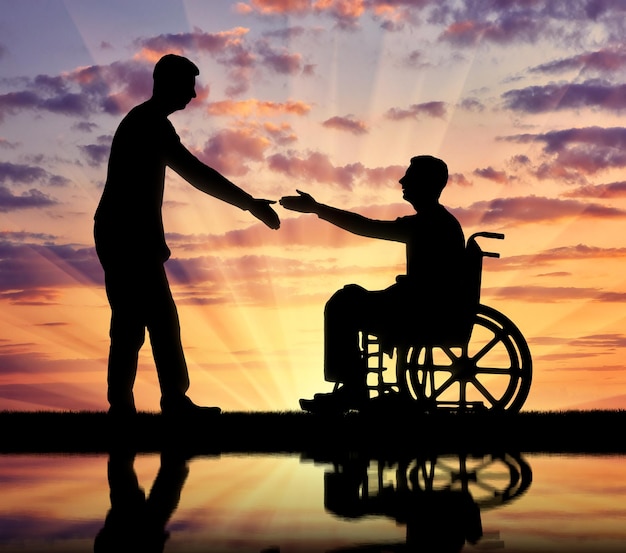 Un hombre está a punto de estrechar la mano de un discapacitado en silla de ruedas. El concepto de respeto y asistencia a las personas con discapacidad en la sociedad