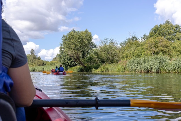 un hombre está remando un kayak con un remo y un cielo azul con nubes en el fondo.