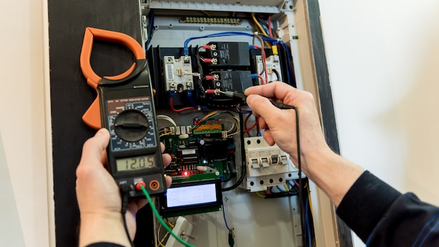 El hombre está reparando el voltaje de la centralita con interruptores automáticos.