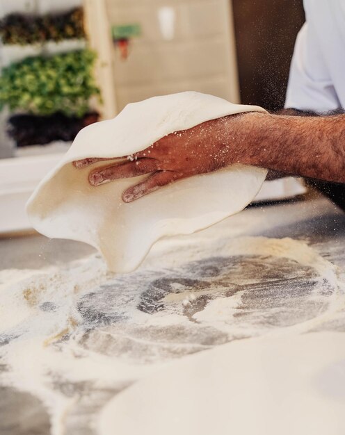 Un hombre está rodando masa de pizza en una cocina.