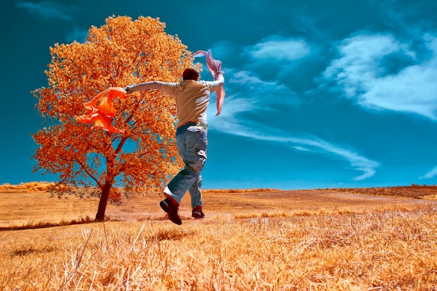 un hombre está saltando en un campo con un árbol en el fondo