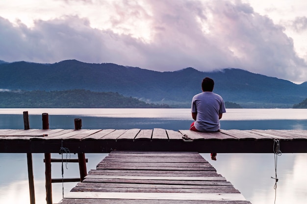 El hombre está sentado y la emoción solitaria con el paisaje en la madrugada.