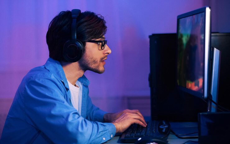 Foto un hombre está sentado frente a una computadora con auriculares jugando un videojuego que está centrado en el