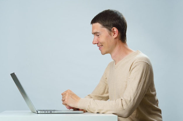 El hombre está sentado a la mesa y usa una computadora portátil para comunicarse en chat o video chat Concepto de redes sociales