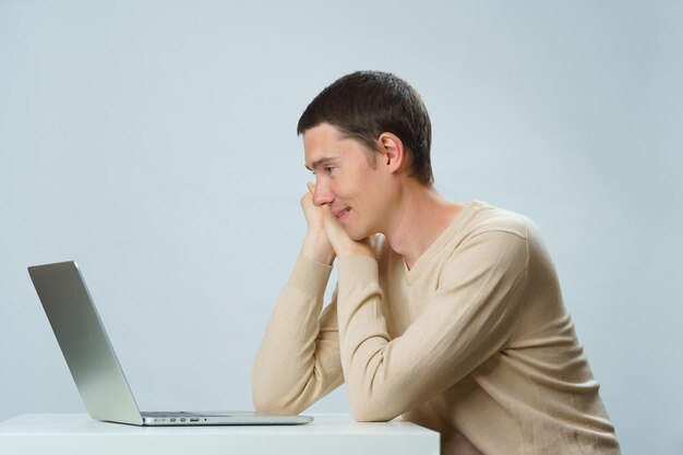 El hombre está sentado a la mesa y usa una computadora portátil para comunicarse en chat o video chat Concepto de redes sociales