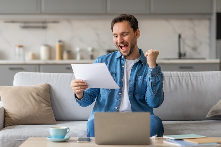 Foto un hombre está sentado en un sofá en una sala de estar moderna sosteniendo un pedazo de papel y sonriendo ampliamente