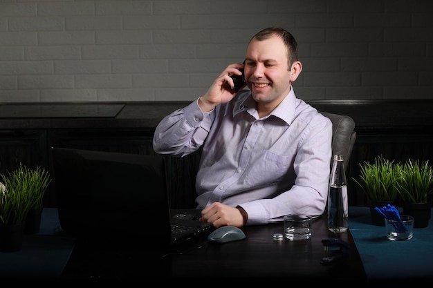 El hombre está sentado en su escritorio y trabaja en una computadora portátil