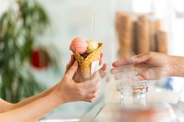 Un hombre está sirviendo un cono de helado de varios sabores a una mujer.