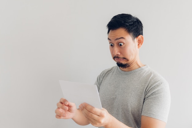 El hombre está sorprendido y sorprendido con el mensaje de correo blanco o la factura.