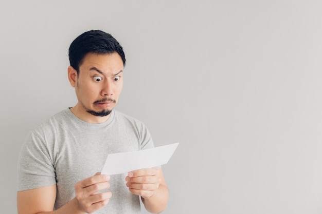 El hombre está sorprendido y sorprendido con el mensaje de correo blanco o la factura.