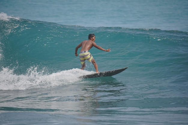 un hombre está surfeando la ola en la playa