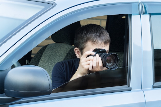 Un hombre está tomando una foto de alguien o algo desde la ventana de un automóvil abierta