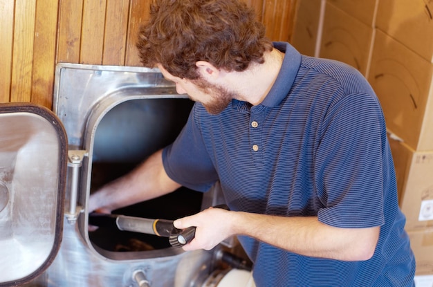 El hombre está trabajando en la fabricación de cerveza cervecera y la productividad en la industria de la destilería y el alcohol Producción de equipos industriales de bebidas alcohólicas y trabajadores masculinos que elaboran bebidas de sidra