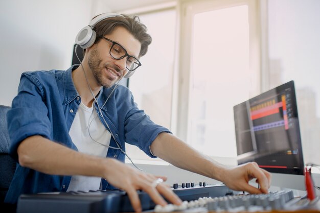 El hombre está trabajando en mezclador de sonido en estudio de grabación