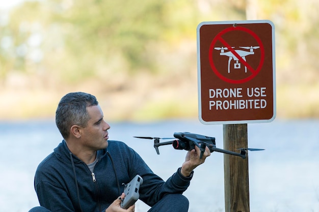 El hombre está triste porque no se le permite volar su parque estatal quadcopter sin área de drones El operador no está autorizado para usar UAS cerca de la señal de restricción