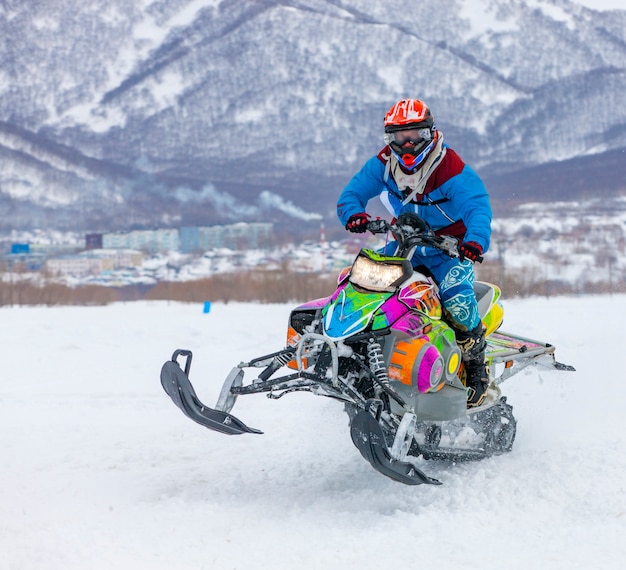 El hombre está volando en una moto de nieve.